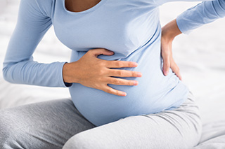 pregnant woman holding her hand on stomach and back