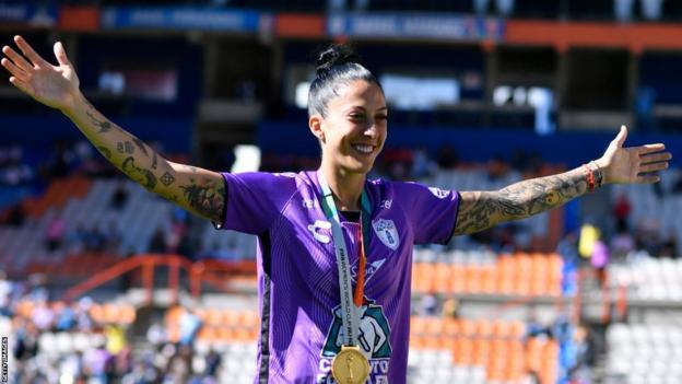 Jenni Hermoso stretches her arms out as she shows off her World Cup winner's medal during a Pachuca game