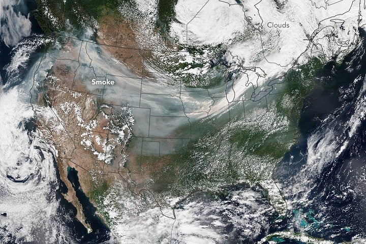  A satellite image of the United States with gray smoke blowing across from the West Coast to the East Coast.